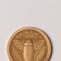 Gold award coin with scarab beetle on front
